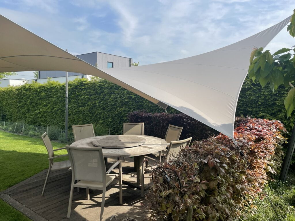 Schaduwdoek op maat boven houten terras met eettafel in moderne tuin